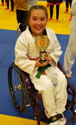 Isabelle wearing her judo uniform and holding a trophy