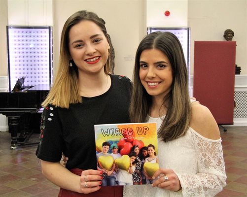 Hannah and Katie, authors of the pacemaker guide for teenagers, holding the booklet between them and smiling