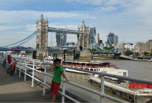 Munkh in central london standing by the Thames with bridges and boats behind him.